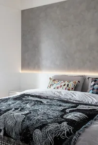 A stylish, minimalist bedroom featuring a bedspread with an abstract dragon design and patterned pillows.