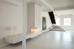 A minimalist room with concrete elements and an industrial-style fireplace.