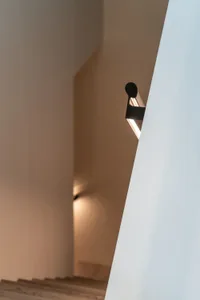 Modern minimalist staircase with wooden treads and a modern light fixture.