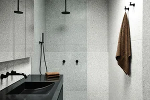 Modern bathroom with gray concrete tiles, black fixtures, and a black sink.