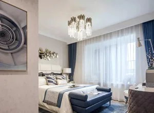 Modern bedroom featuring a bed with fabric headboard, blue leather bench, and glass chandelier.