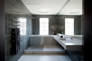 A minimalist bathroom featuring grey tiles, concrete elements, and a contemporary design.