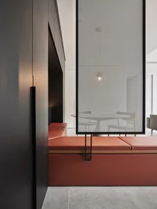 Detailed view of a modern living space featuring a metal perforated panel wall, orange seating, and white furnishings.