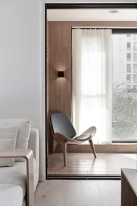 Modern interior design featuring a wooden living area with a sleek armchair and a comfortable sofa, illuminated by warm light