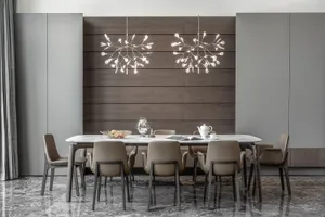 Modern dining room with marble table and chairs, featuring hanging chandeliers and grey cabinetry.