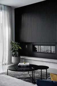 A modern minimalist living room with a dark accent wall, concrete floor, and wood coffee table.