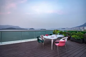 A modern rooftop deck with colorful chairs and a table overlooking a scenic landscape.