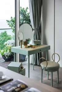 A modern vanity with wooden legs, a circular mirror, and a green cushioned stool.