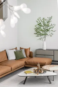 A cozy Scandinavian living room with a brown leather sectional sofa, green plant, and modern decor.