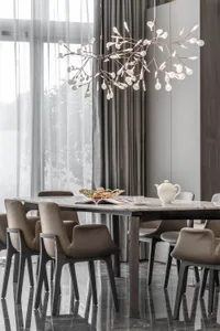 Modern dining room featuring a marble table and walnut chairs with a unique chandelier and an open window with sheer curtains