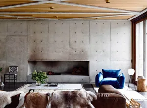 A modern living room with concrete walls and a fireplace.
