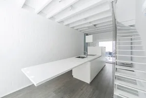 Modern, minimalist kitchen with white cabinets and sleek design.