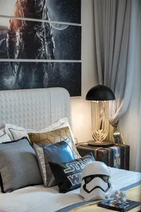 Bedroom featuring a white upholstered headboard with various pillows and a stormtrooper helmet on the bed.