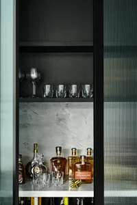 Modern bar shelf featuring marble and glass with various bottles of alcohol