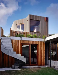 Modern residential exterior featuring wood and concrete materials.