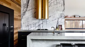 Modern kitchen with concrete countertops, minimalist design, and marble backsplash.