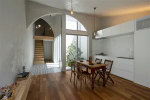 Industrial-style residential kitchen with white tiled walls, hardwood flooring, and wooden cabinets.