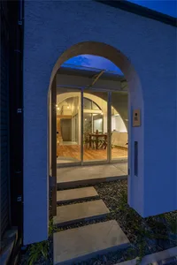 Concrete entrance with archway and glass door, viewed from the outside at dusk.