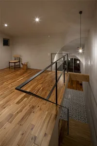 Minimalist living room with wooden flooring and a small chair in a corner.