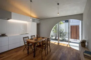 A minimalist residential kitchen with wooden elements and a view of the courtyard.