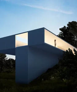 A modern, minimalist concrete building with a large open space illuminated from within.