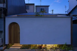 Modern exterior wall with concrete finish and small garden.