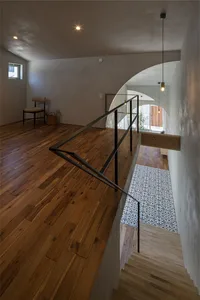 A modern house interior with a wooden staircase, glass railing, and patterned floor tiles.