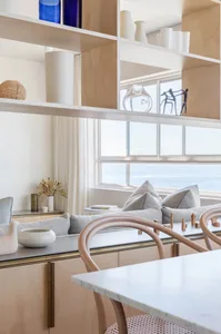 Modern kitchen featuring a marble countertop and wooden furniture with a view of the sea.