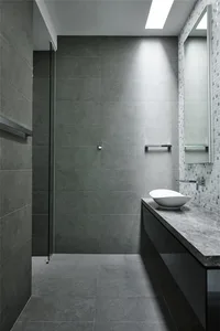 A modern, minimalist bathroom featuring concrete tiles and a sleek, bowl-shaped sink.