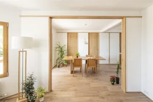 Minimalist dining room with wooden furniture and green plants.