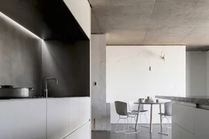 Modern kitchen with minimalist design, featuring concrete countertops and white fixtures.