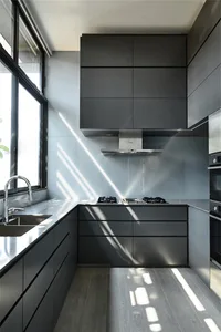 Modern kitchen featuring sleek black cabinets and glass countertops.