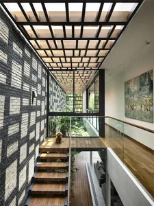 A modern interior with a wooden staircase leading to a garden view, featuring brick walls and large windows.