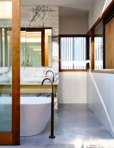 Modern bathroom featuring minimalist design with marble finishes and a freestanding bathtub.