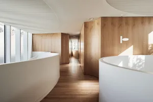Modern office space featuring curved wooden walls and white reception desks.