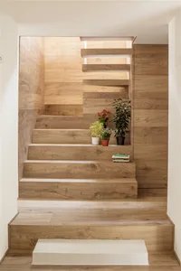 Rendering of a modern wooden staircase with plants and books on the steps.