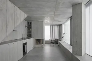 A modern, minimalist kitchen with concrete countertops and walls.