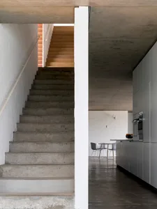 A modern living room with concrete walls and floors, featuring clean lines and minimalist design.
