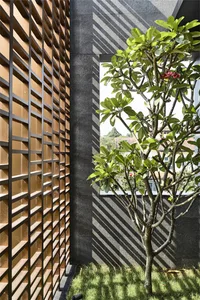 Modern exterior with wooden panel cladding and a tree with red flowers in the foreground.
