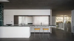 Modern kitchen featuring concrete countertops and white brick walls.