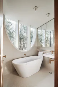 A modern bathroom featuring a white freestanding bathtub and a sink with a metallic faucet, surrounded by white ceramic tiles
