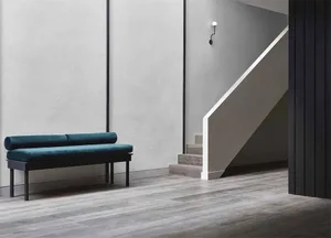 Modern minimalist interior design featuring a wooden floor and a turquoise cushioned bench.