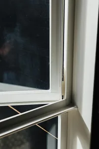 Close-up of a minimalist metal-framed window with sunlight shining through the glass.