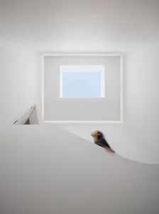 A minimalist white space rendered in 3D with concrete elements and a large window.