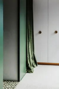 Modern house with green velvet curtains, wooden closet doors, and patterned green and white tiled floor.