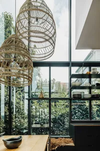 Modern industrial kitchen with textured pendant lights and large windows overlooking green foliage.