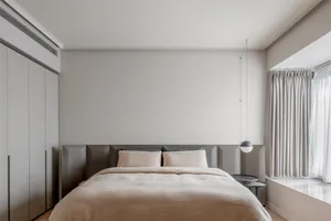 Modern minimalist bedroom featuring a textured fabric bed, neutral color palette, and sleek furniture.