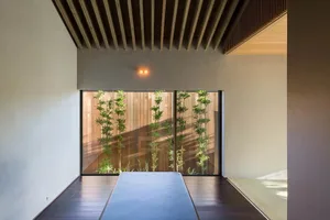 A modern minimalist living room with a garden view through a large sliding glass door, featuring dark wooden flooring, minima