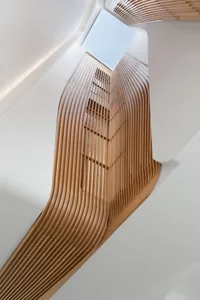 A modern staircase with wooden slats leading up to a skylight.