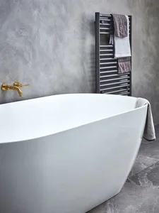 Modern minimalist bathroom featuring a freestanding tub in a freestanding position, with a gray wall and towel rack.